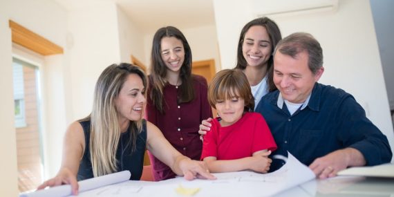 A joyful family gathered around a table reviewing a home blueprint together.